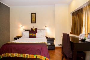 a hotel room with a bed and a desk at Hotel Bon Voyage in Lagos