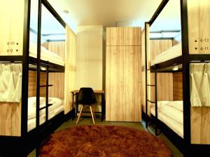 a room with two bunk beds with a chair and a table at Namba Guesthouse HIVE in Osaka