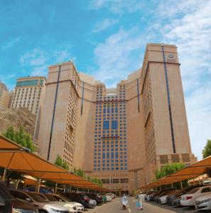 فندق أنجم مكة في مكة المكرمة: مبنى كبير به سيارات تقف في موقف للسيارات