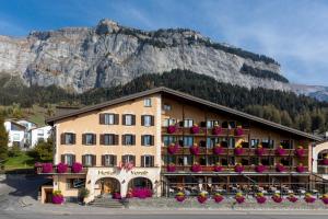 un gran edificio con flores frente a una montaña en Hotel Vorab - Kulinarische Vielfalt, en Flims