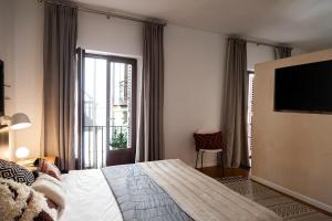 Una habitación de hotel con una cama y un televisor de pantalla plana. en Welldone Cathedral, en Sevilla