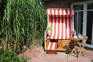 une chaise rouge et blanche assise sur une terrasse dans l'établissement Ferienwohnung Robben Deele, à Sankt Peter-Ording