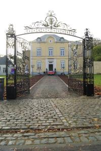 un cancello aperto per un grande edificio giallo di Kasteel B&B Sint-Bartel a Geraardsbergen