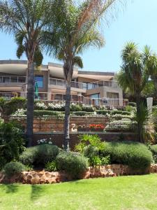 een gebouw met palmbomen voor een tuin bij Over The Moon Guesthouse in Johannesburg