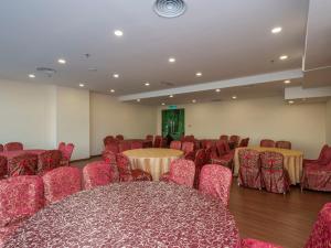 una sala de conferencias con sillas y mesas rojas y una pantalla en Hotel Holmes Gp, en Nusajaya
