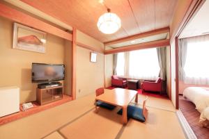 um quarto com uma mesa, uma televisão e uma cama em Fuji Green Hotel em Fuji