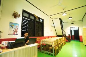 a man sitting at a table using a laptop computer at Y Not Laos Hostel in Luang Prabang