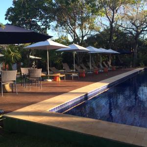 a swimming pool with tables and umbrellas and chairs next to a swimming pool at Apto incrível em condomínio lindo in Praia do Forte