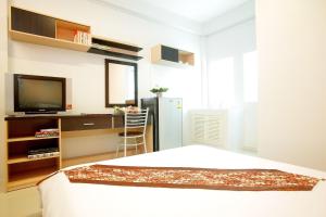 a bedroom with a bed and a desk and a television at Smile Inn in Bangkok