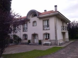 une maison blanche avec un banc devant elle dans l'établissement LASAILEKU, à Bilbao