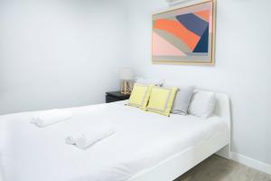 Un dormitorio blanco con una cama blanca y una pintura en Cruz Apartment, en Madrid