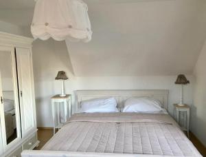 a bedroom with a white bed with two lamps at Ferienhaus Strandgut in Zingst