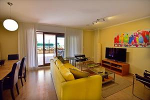 a living room with a yellow couch and a television at New apartamento Bajo en Isla de la Toja. in Isla de la Toja