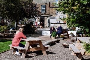 Una donna seduta a un tavolo da picnic in un parco di The Garret Hotel a Kirkcudbright