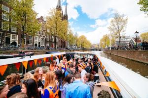 un gran grupo de personas en un barco en un canal en The ESN Kingsday Campsite, en Ámsterdam