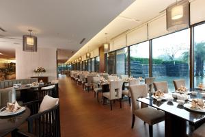 um restaurante com mesas, cadeiras e janelas em Evergreen Resort Hotel - Jiaosi em Jiaoxi