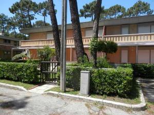 a building with trees and a trash can in front of it at Appartamenti MareMaremma in Principina a Mare