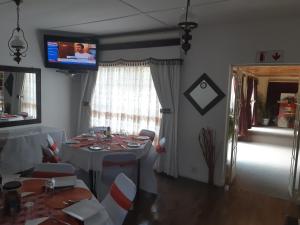 a dining room with a table with chairs and a television at Mentor Guest house in Queenstown