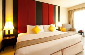 ein Hotelzimmer mit einem großen Bett mit gelben Kissen in der Unterkunft Intimate Hotel Pattaya - SHA Extra Plus in Pattaya
