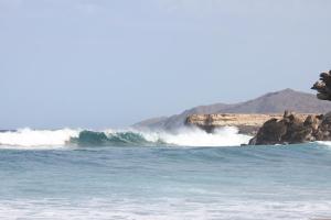 a wave in the ocean next to a beach at Wellenkind Surfschool in La Pared