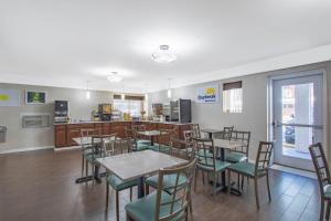a dining room with tables and chairs and a kitchen at Days Inn by Wyndham Elmsford in Elmsford
