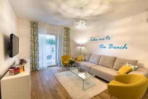 a living room with a couch and a sign that reads take me to the beach at Apartments Tamaris in Klek