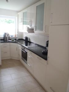 a kitchen with white cabinets and black counter tops at Borkumperle in Borkum