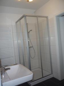 a shower with a glass door next to a sink at Borkumperle in Borkum