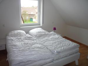 an unmade bed in a room with a window at Borkumperle in Borkum