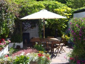 uma mesa com um guarda-sol num jardim com flores em Riverside B&B em Cushendall