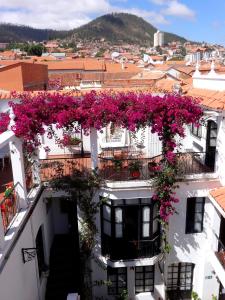 un balcón con flores rosas en un edificio blanco en El Hotel de Su Merced, en Sucre