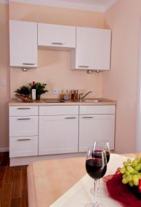 a kitchen with white cabinets and a glass of wine at Pension Weindl in Notzing