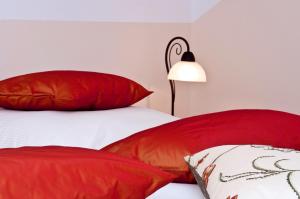 a bedroom with red and white pillows and a lamp at Pension Weindl in Notzing