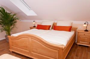 a bedroom with a wooden bed with white sheets and orange pillows at Pension Weindl in Notzing