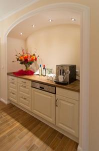 a kitchen with white cabinets and a counter with a vase of flowers at Pension Weindl in Notzing +12 photos