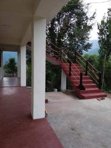 a red staircase in a house with mountains in the background at Delight Homestay in Cherrapunji
