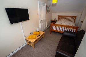 a small living room with a couch and a bed at Clara Lodge Guesthouse in Dunfermline