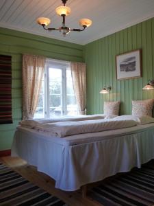 ein großes Bett in einem grünen Schlafzimmer mit einem Fenster in der Unterkunft Kvebergsøya Gard in Grimsbu