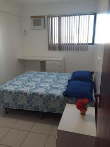 Un dormitorio con una cama con sábanas azules y una mesa. en Apartamento Edifício Setai, en Maceió