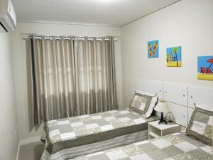 een slaapkamer met 2 bedden en een raam bij Don Rafael 02 dormitórios, 80m mar, Mariscal in Bombinhas