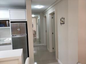 a kitchen with a stainless steel refrigerator and a hallway at Don Rafael 02 dormitórios, 80m mar, Mariscal in Bombinhas