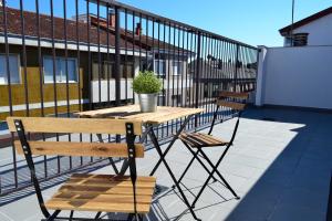 Una mesa de madera y dos sillas en un balcón. en Hotel Alda Estación Ourense, en Ourense