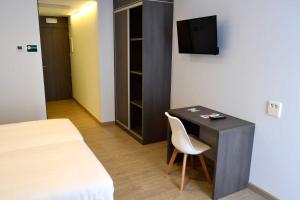 a room with a desk with a chair and a television at Hotel Alda Estación Ourense in Ourense