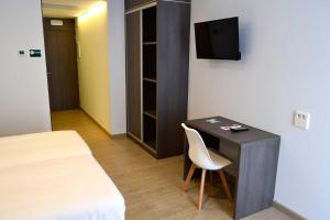 Una habitación con un escritorio con una silla y un televisor. en Hotel Alda Estación Ourense, en Ourense
