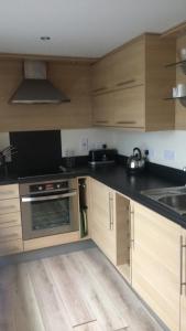 a kitchen with wooden cabinets and a stove top oven at Sandy bay 56 sunrise drive first floor apartment in Filey +3 photos
