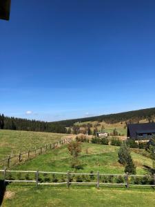 een houten hek in een veld met een huis bij apartmán Oblík - penzion Kilián in Kvilda