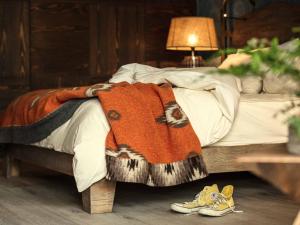 a bed with a blanket and shoes on the floor at Valsana Ferienwohnungen Arosa in Arosa