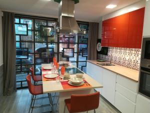 ポルトにあるKris Apartments Portoのキッチン(赤いキャビネット、テーブル、椅子付)