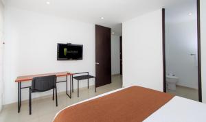a bedroom with a desk and a tv on the wall at 122 Plaza Apartahotel in Bogotá