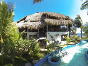 un complejo con piscina y un edificio con techo de paja en Marbella Eco Lodge, en Monterrico